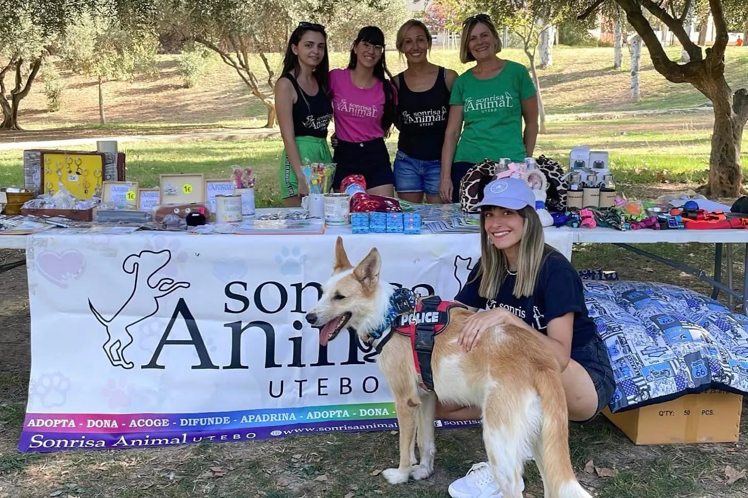 Voluntarias de Sonrisa Animal preparando artículos solidarios junto a un perro.
